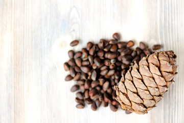 Pine cone and nuts on light wooden background. Healthy eating, organic food, vegetarian concept.