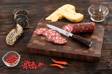 Sliced cheese, sausage and bread on a wooden cutting board