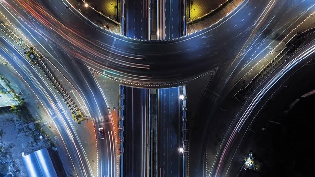 Hyperlapse timelapse of night city traffic on 4-way stop street intersection circle roundabout in bangkok, thailand. 4K UHD horizontal aerial view.