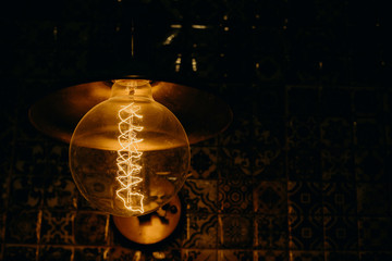 Glass retro-bulb Edison and dark background with designer light in loft interiors.