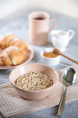 Oatmeal with milk, and croissants with honey on the table. Tasty breakfast.