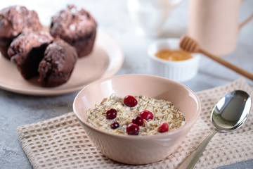 Oatmeal with milk and berries, and muffins with honey on the table. Tasty breakfast.