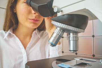 student girl looking in a microscope, science laboratory concept