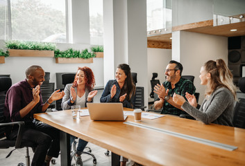 Diverse business team clapping hands and smiling during boardroom meeting