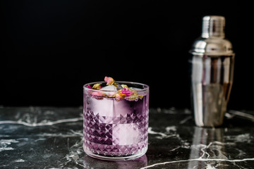 Pink Gin Tonic Cocktail with Dried Rose Buds and Ice in Glass Cup