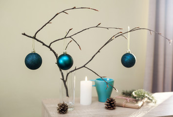 Christmas home decorations. Blue balls, branch of tree, gift box, candle, pine cones, DIY idea for interior design.