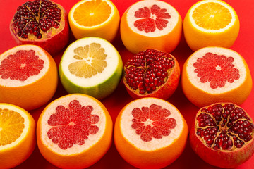 Grapefruit, orange, pomegranate, citrus sweetie on red background.
