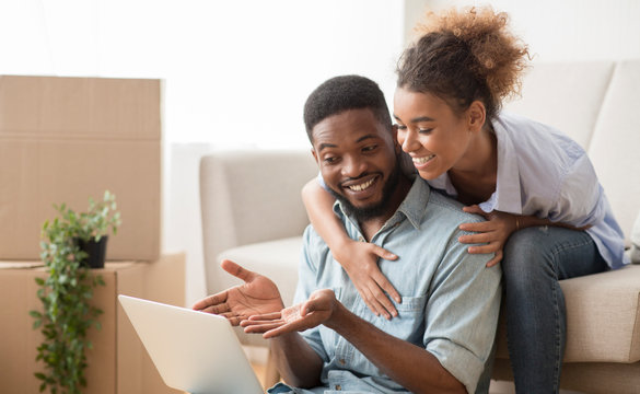 Husband Using Laptop Showing Something Wife Sitting On Couch Indoor
