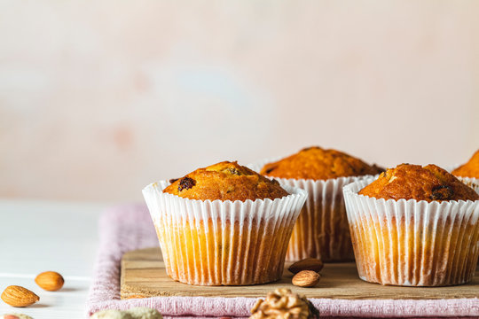 Vanilla caramel muffins in paper cups on white wooden background.