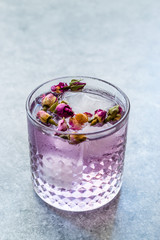 Pink Gin Tonic Cocktail with Dried Rose Buds and Ice in Glass Cup