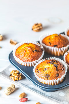 Vanilla caramel muffins in paper cups in bakeware on white wooden background