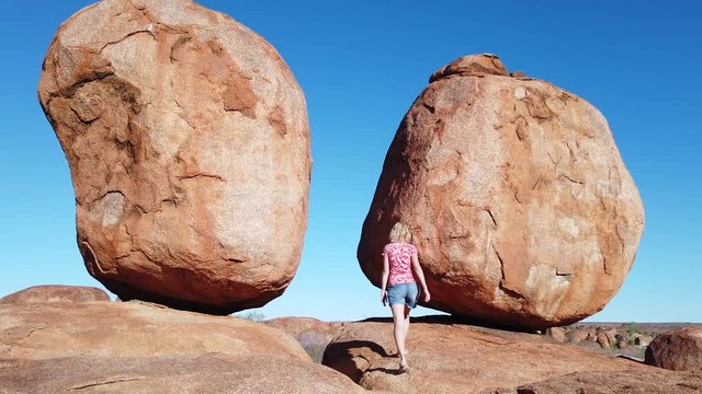 girl at Devils Marbles, Northern Territory: the Eggs of mythical Rainbow Serpent. tourist girl at iconic landscape of Outback, one of Australia's most famous natural wonders