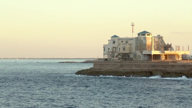 Coast Guard Fortress on a cliff. Large stone building. Around the Mediterranean Sea. The waves hit the rocks