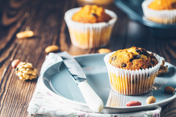 Vanilla caramel muffins in paper cups on plate on dark wooden background