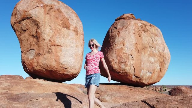 girl walking at Devils Marbles, Northern Territory: Eggs of mythical Rainbow Serpent. Tourist woman walking at iconic landscape of Outback, one of Australia's most famous natural wonders