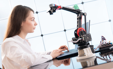 A young woman writes an algorithm for the robot arm. Science Research Laboratory for Robotic Arm...