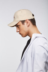 Cropped side photo of a dark-haired man, wearing beige baseball cap with lettering 
