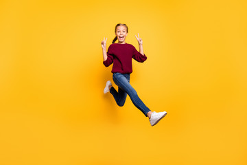 Full length body size view of her she nice attractive cheerful cheery playful pre-teen girl having fun jumping showing double v-sign isolated on bright vivid shine vibrant yellow color background