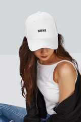 Cropped upward shot of a dark-haired girl, wearing white baseball cap with lettering 