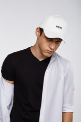 Cropped front view shot of a dark-haired man, wearing white baseball cap with lettering 