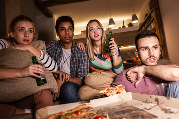 Group best friends sitting at home  watching a scary movie .Watching tv show and eating pizza.