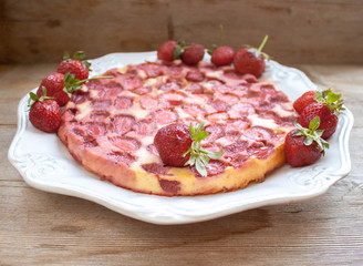 Round strawberry pie with fresh strawberries on white plate dish on wooden table background