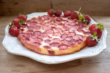 Round strawberry pie with fresh strawberries on white plate dish on wooden table background