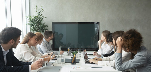 Businesspeople watching an online presentation on tv screen