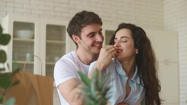 Young couple flirting at home. Smiling man and woman eating strawberry.