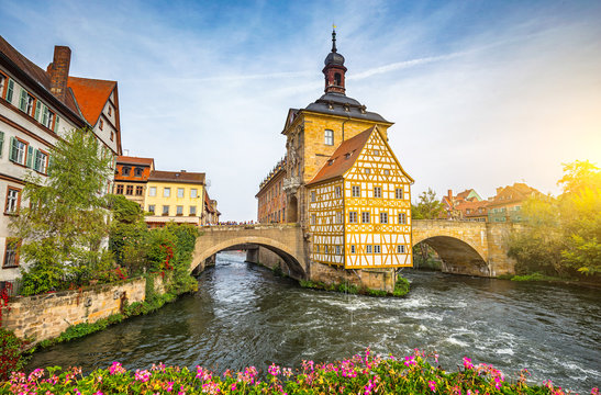 Classic panoramic view of famous Bamberg town hall with idyllic Regnitz river in the historic city center on a  beautiful day in golden evening light at sunset in summer, Bavaria, Germany