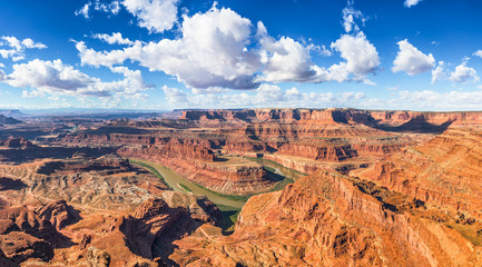Beautiful panoramic view of famous cliffs and canyons in Dead Horse Point State Park and Colorado River meanders on a sunny day with blue sky and scenic clouds in summer, American Southwest, Utah, USA