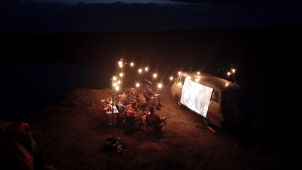 Friends Watching Movie on Screen in Campsite