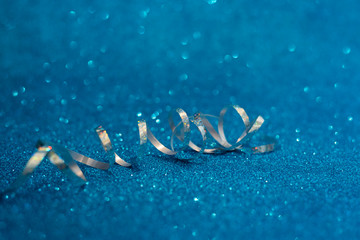 Silver streamers on blue glittering background. Christmas and New Year holidays concept. Copy space