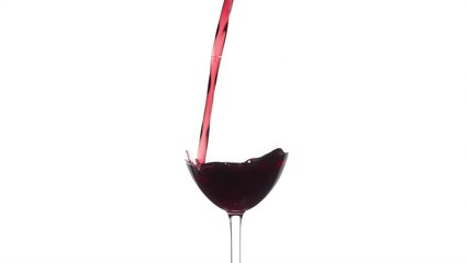 Slow motion of pouring red wine from bottle into goblet on white background