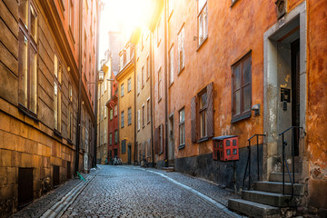 Classic view of scenic alleyway Prästgatan (The Priest's Street) with traditional colorful houses in Stockholm's historic Old Town of Gamla Stan in beautiful golden morning light, Stockholm, Sweden - obrazy, fototapety, plakaty