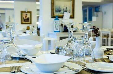 glasses plates and Cutlery on restaurant table in white close-up, traditional Greek restaurant, Europe, Greece.