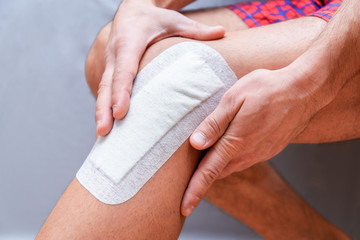 medical plaster is glued to the knee of the male leg after surgery