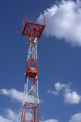 Tower connection with the mast and antennas against the blue sky with clouds. Transmission and reception of signals
