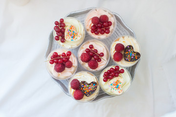 Assorted home made desserts in cups with whipped cream and fresh berries, strawberries, blueberries, raspberries, decorated with chocolate hearts. 