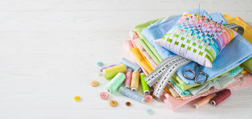 Needle box, threads and cotton fabrics for sewing. White background.