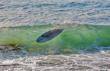 Empty surfboard floating in a wave