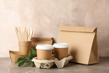 Eco - friendly tableware and paper bag on grey table, space for text