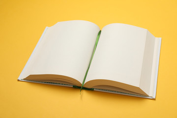 Opened empty book on yellow background, space for text