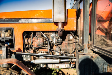 Old orange farm tractor, side view with visible engine, close-up.