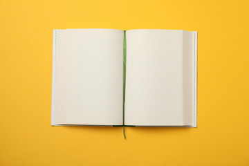 Opened empty book on yellow background, space for text