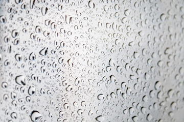 Drops of water on the glass against a blurred cloudy sky background on a rainy day. Selective focus