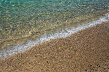 Beautiful clean transparent water of Aegean sea splashing softly at scenic sandy beach outdoor. Horizontal color photography.