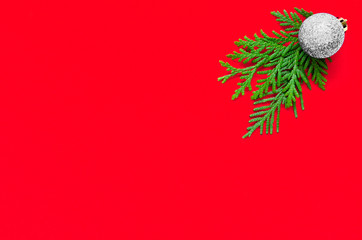 Christmas minimal composition. Christmas silver ball and fir tree branch on red background. Flat...