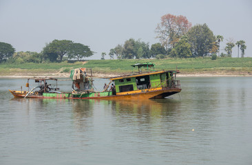 Floating dredge for the extraction of gold and precious stones, Irrawaddy river, Burma. Copy space for text.