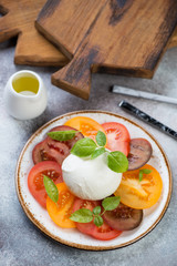 Plate with caprese salad over beige stone background, vertical shot, selective focus